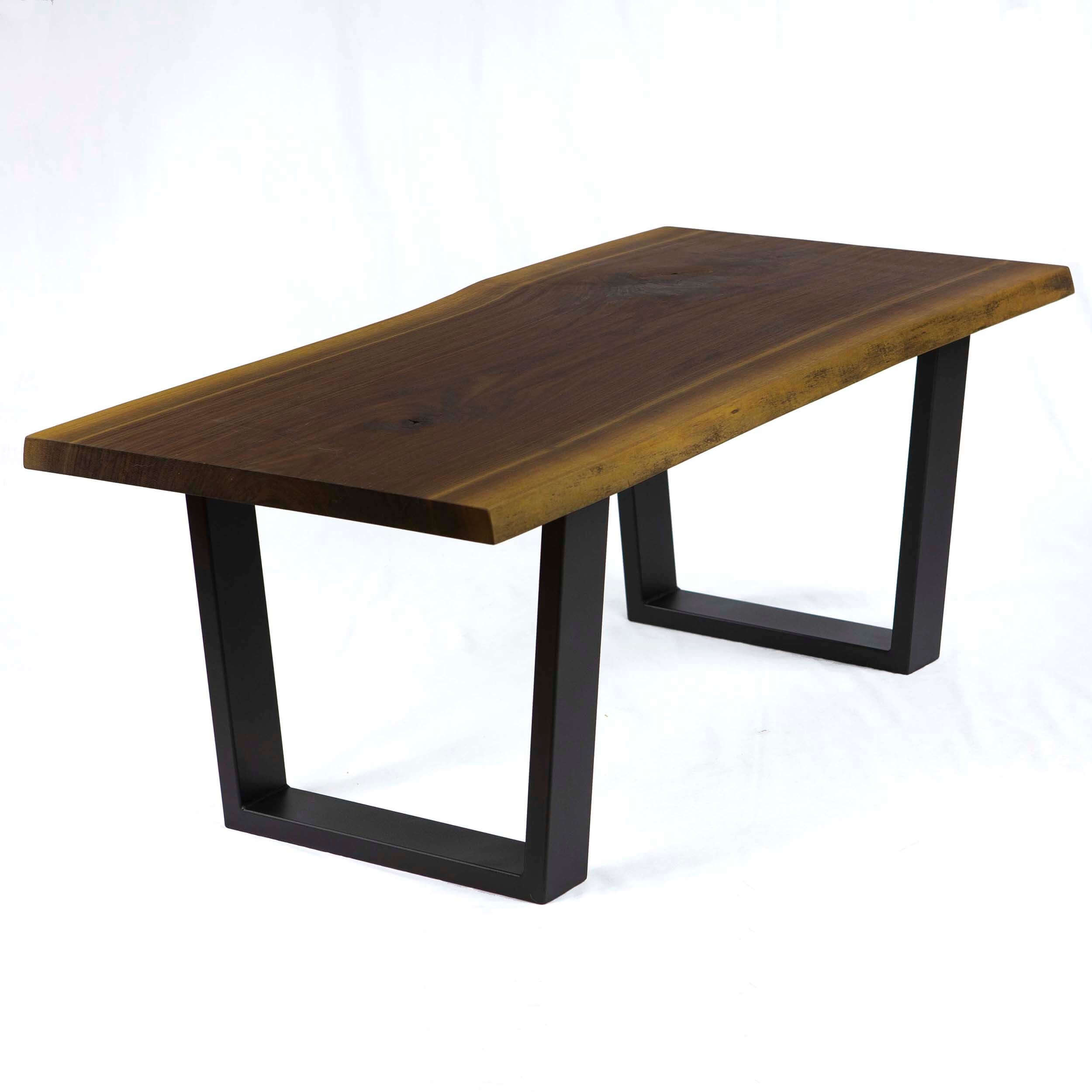 Matte black coffee table legs with trapezoid frames holding a dark wood top