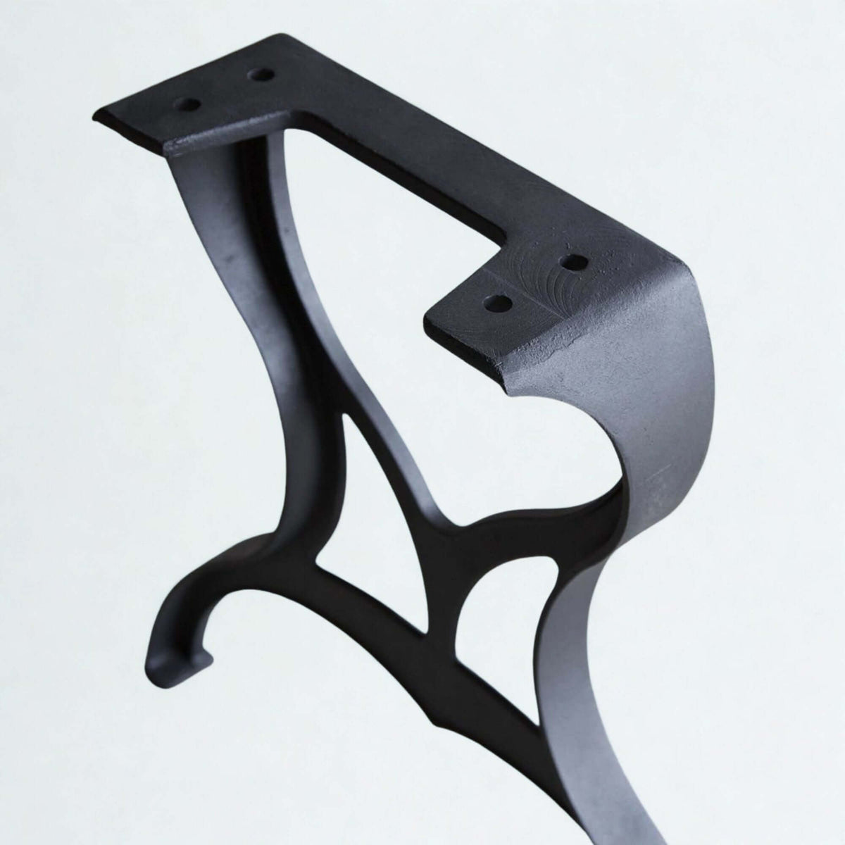 Matt black cast iron dining table leg bracket, close-up of openwork frame