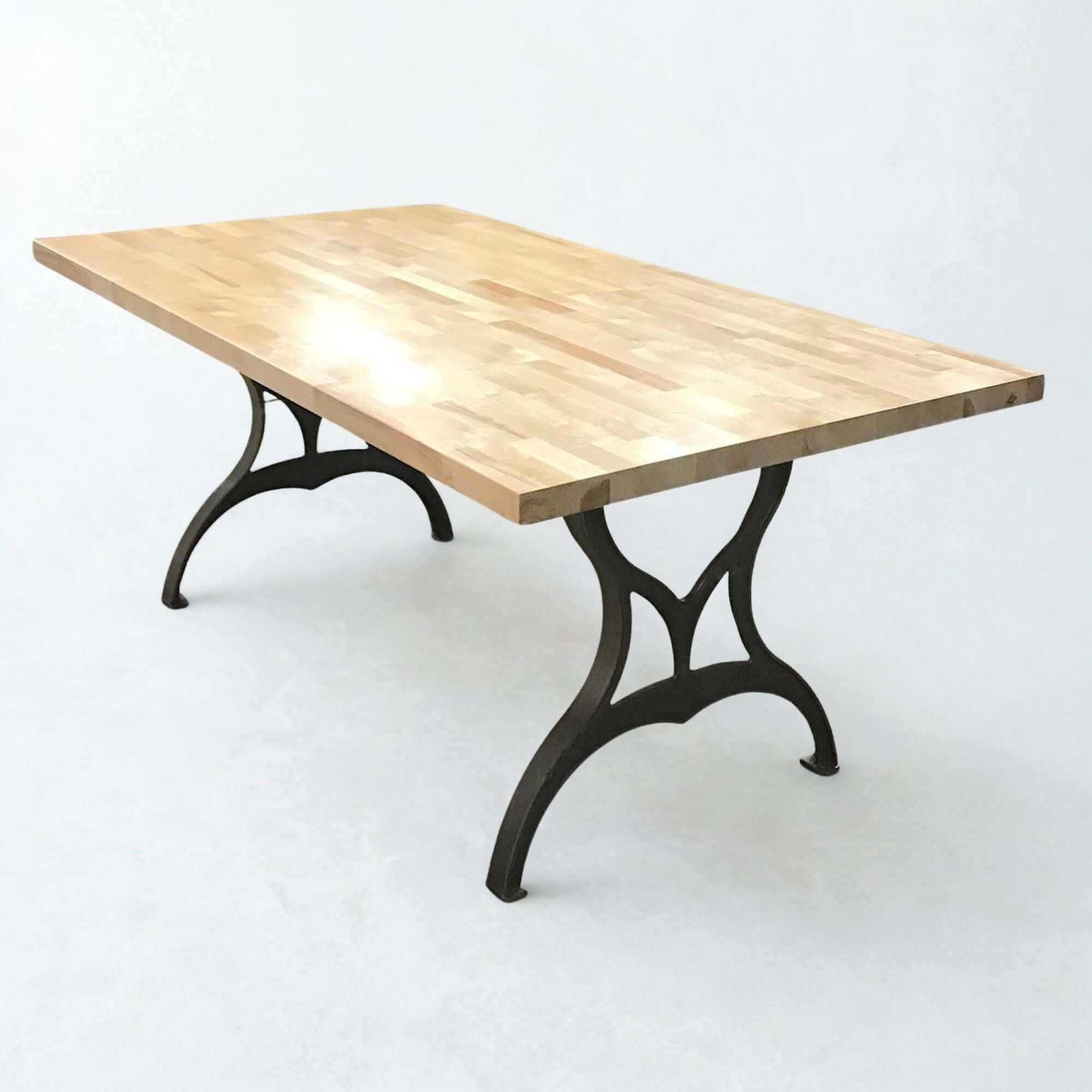 Cast iron dining table legs with matte black finish, under a wood tabletop