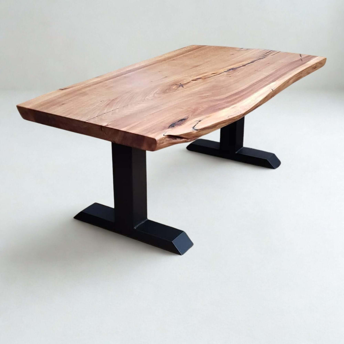 Black powder-coated tee-shaped coffee table legs supporting a wooden tabletop