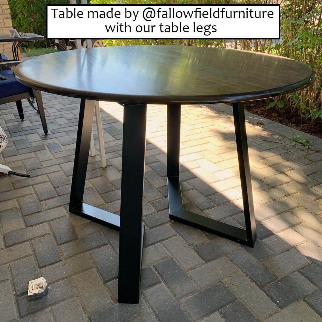 Dining table legs installed under round top, black steel, pair