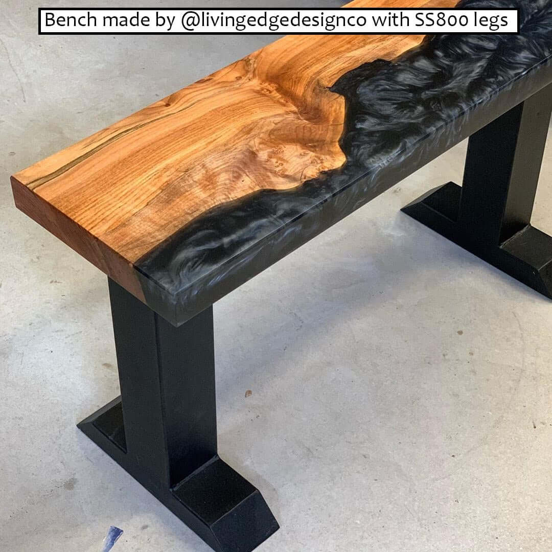 Black powder-coated bench legs supporting a wooden bench top with solid base feet