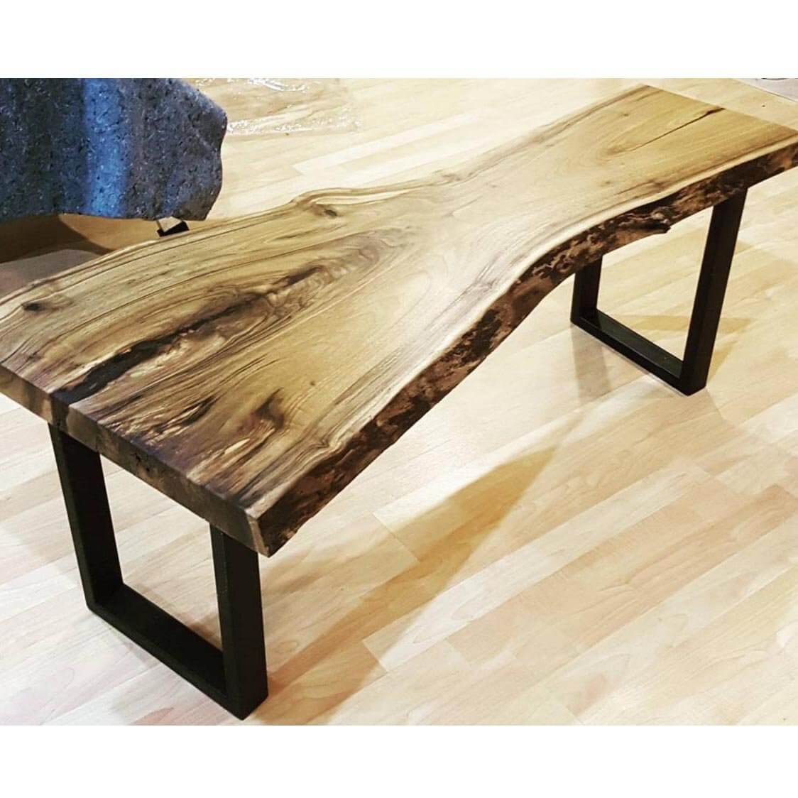 Black metal U bench legs with open frame, supporting a wooden bench top